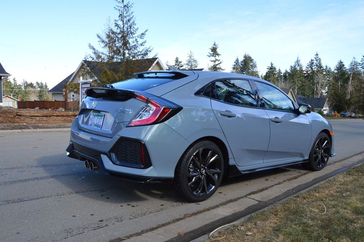 the rear end of a silver honda civic hatchback parked in front of a house