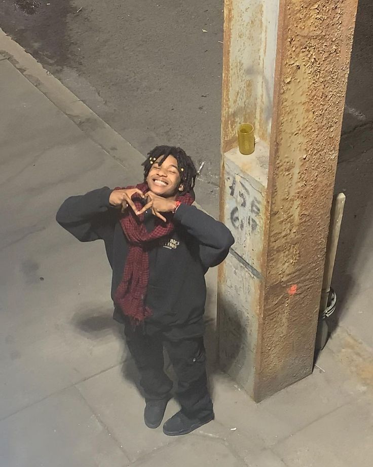 a woman standing next to a pole on the sidewalk