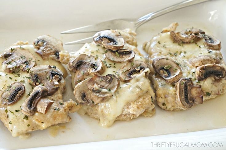 three pieces of chicken covered in mushrooms and gravy with a fork on the side