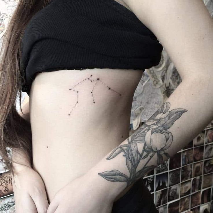 a woman's stomach with a flower tattoo on her side and the zodiac sign