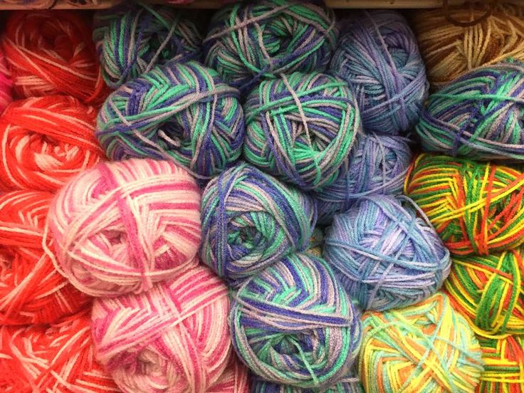 many balls of yarn are stacked on top of each other in different colors and sizes