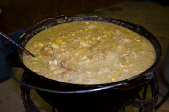 a pot filled with soup sitting on top of a stove next to a pan full of food