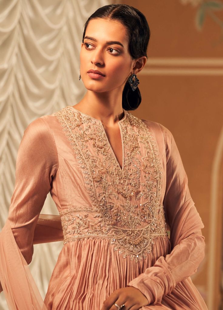 Elevate your elegance with this dusky pink long anarkali, crafted from luxurious fine silk. Adorned with intricate embroidery, its flowing silhouette offers grace and sophistication. Complemented by a matching net dupatta, also embellished with delicate embroidery, this ensemble is perfect for any special occasion, blending timeless beauty with modern charm. Formal Pink Anarkali Set With Intricate Embroidery, Elegant Embellished Pink Anarkali Set, Pink Embroidered Anarkali Dupatta, Pink Semi-stitched Anarkali Set With Intricate Embroidery, Pink Churidar, Pink Embellished Anarkali Embroidered Fabric, Churidar Sleeves, Ridhi Mehra, Pink Anarkali