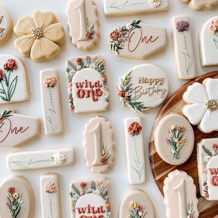 decorated cookies with the words happy one on them and flowers are laid out next to each other