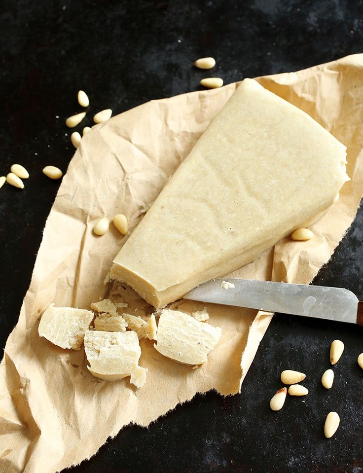 a piece of cheese sitting on top of a piece of paper next to a knife