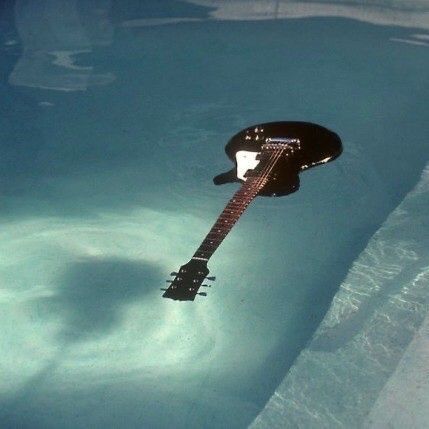 an electric guitar floating in the water with it's neck hanging down from its neck