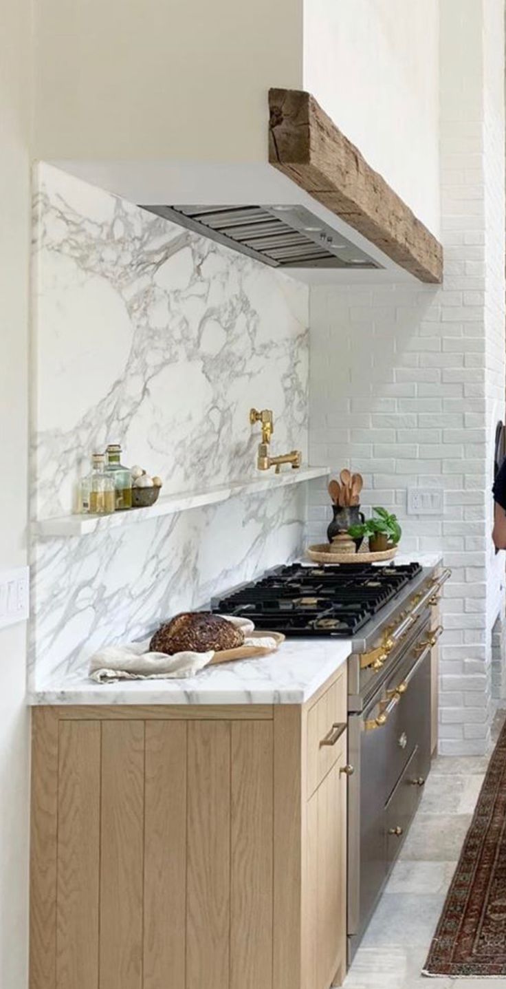 a woman standing in a kitchen next to an oven and counter top with white marble on it