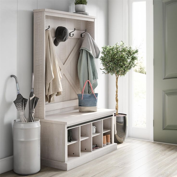 a coat rack with hooks and two coats hanging on it next to a potted plant