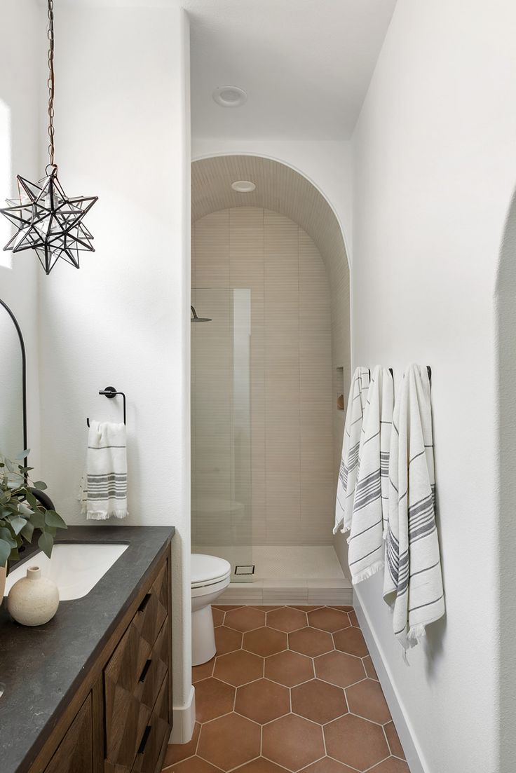 a bathroom with white walls and brown tile flooring next to a walk in shower