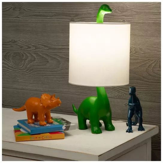 two dinosaur figurines sitting on top of a table next to a white lamp