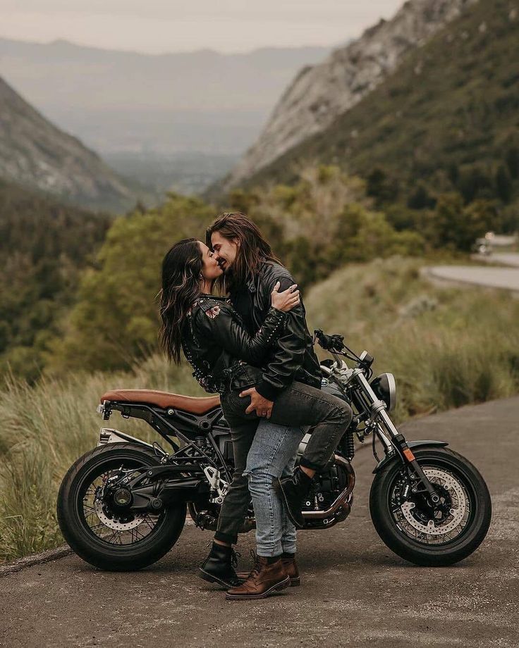 a man and woman kissing while sitting on a motorcycle