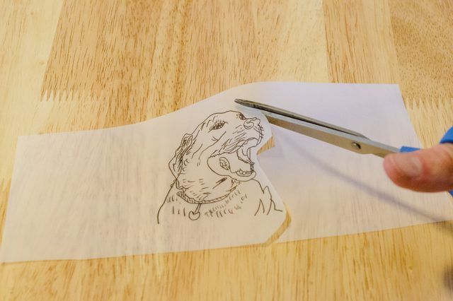 a person cutting paper with a pair of scissors on top of it and a drawing of a dog