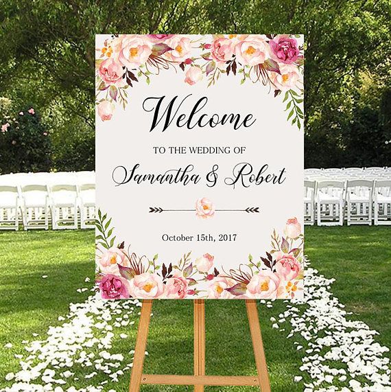 a welcome sign with flowers on it in front of white chairs and green lawns