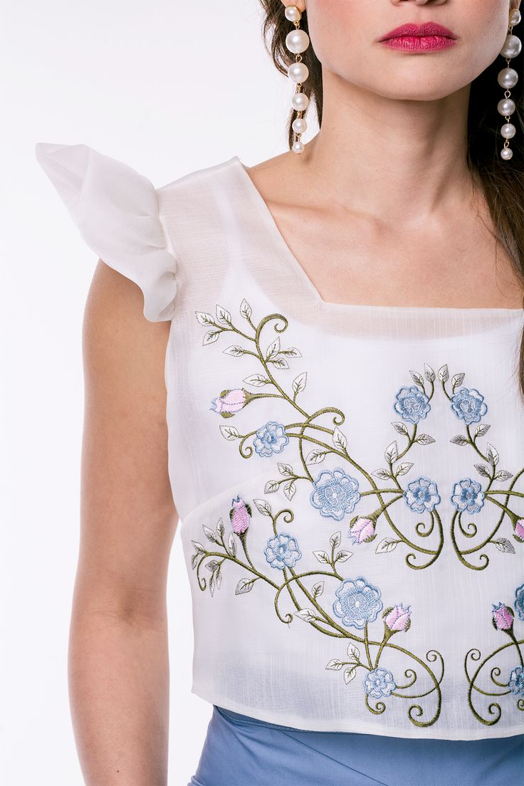 The Vella Crop Top is a luxurious embodiment of effortless elegance. Crafted from sumptuous cocoon silk in a timeless ivory hue, this top exudes sophistication. Its minimalist design is elevated by intricate floral embroidery, inspired by the vibrant beauty of the Philippines, which adds a touch of bohemian charm. Luxurious cocoon silk fabric Timeless ivory hue Intricate floral embroidery Modern cropped silhouette Versatile styling options Limited availability due to handmade production Model is Elegant Embroidered Cream Top For Summer, Elegant Silk Tops With Intricate Embroidery, Feminine Floral Embroidered Tops For Weddings, Feminine Embroidered Tops For Wedding, Elegant Summer Top With Tonal Embroidery, Elegant Cream Embroidered Summer Top, Feminine Blouse With Floral Embroidery For Wedding, Elegant Sleeveless Tops With Intricate Embroidery, Chic Floral Embroidered Dress For Wedding