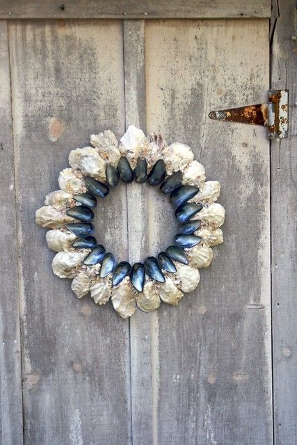 a wreath made out of seashells hangs on the side of a wooden door