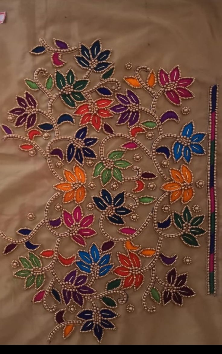 an embroidered cloth with colorful flowers and leaves on the side, sitting on a table