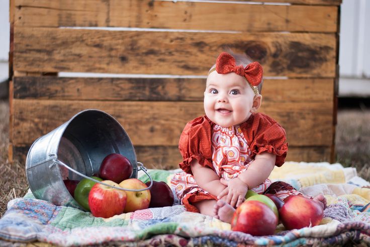 a baby sitting on a blanket with apples