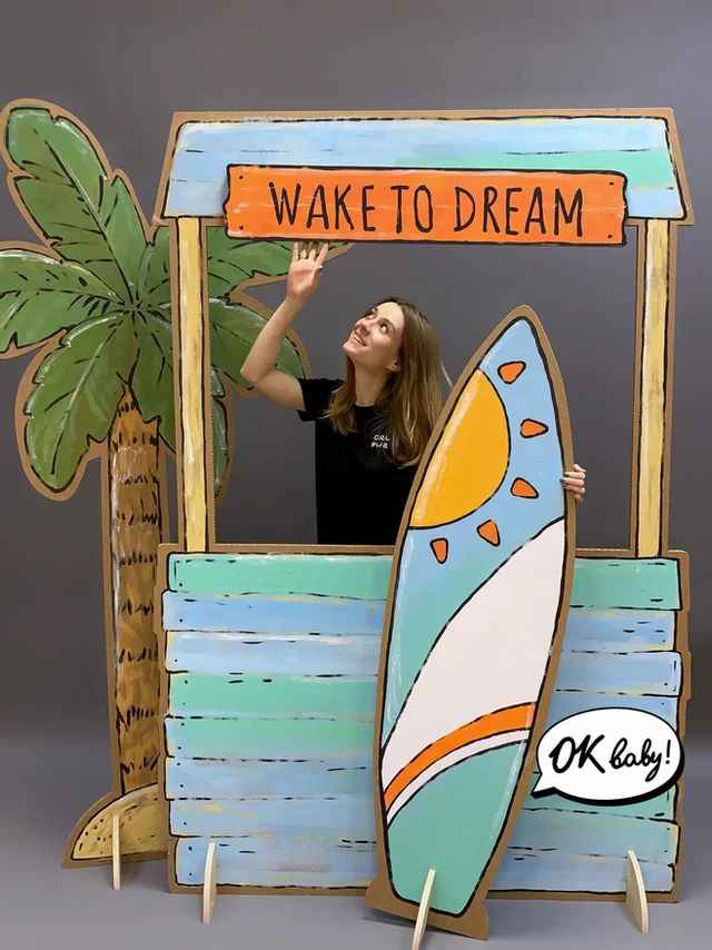 a woman standing in front of a fake surfboard with the words wake to dream on it