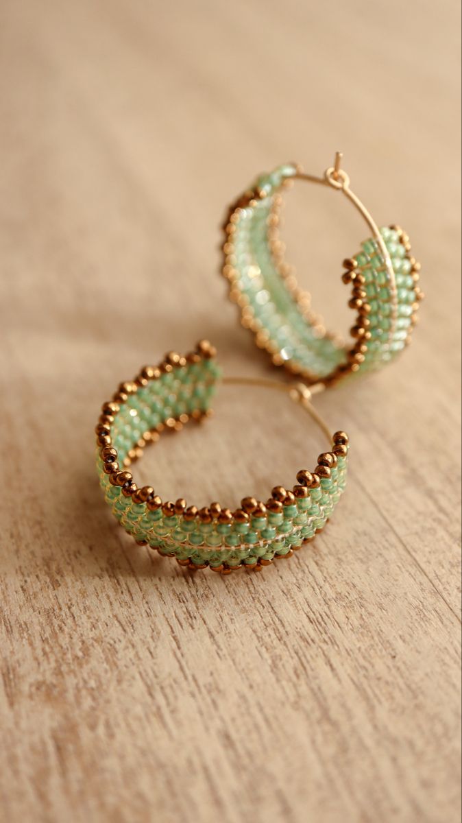 green beaded hoop earrings sitting on top of a wooden table