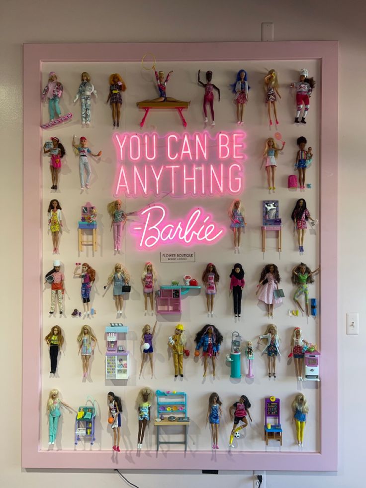 a display case with barbie dolls and neon sign that says you can be anything barbie