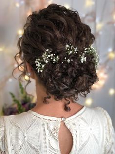 the back of a woman's head with flowers in her hair and pearls on it