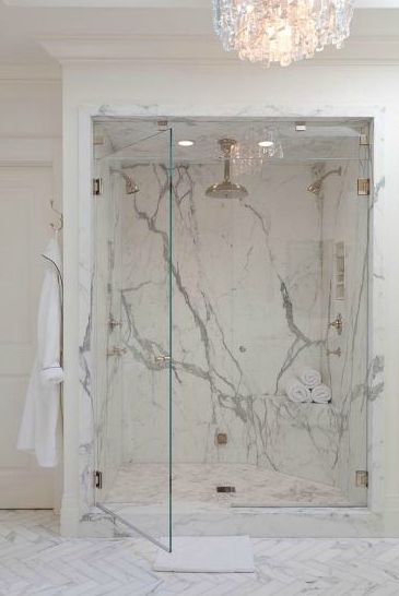 a bathroom with marble walls and flooring in the shower area, along with a chandelier