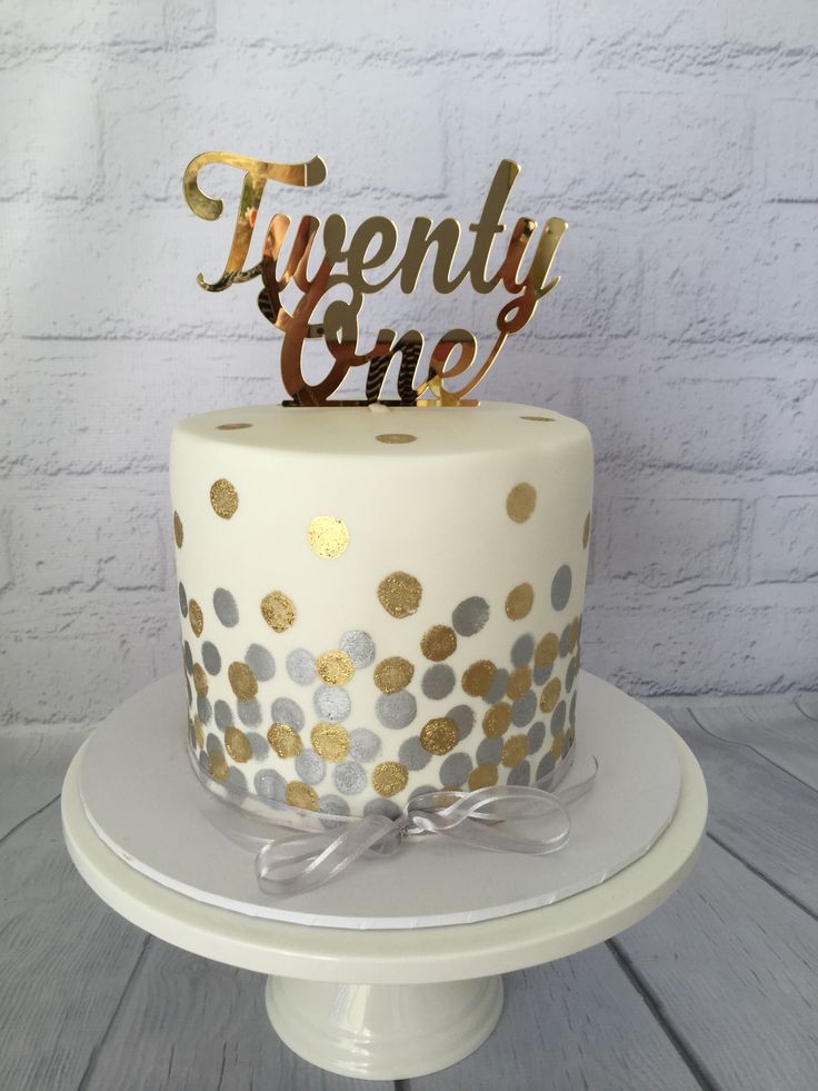 a white cake with gold and silver polka dots on the top that says twenty one