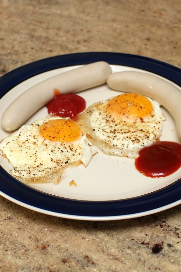 two eggs and sausage on a plate with ketchup