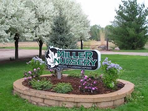 a sign for miller nursery in the middle of a flower bed with purple and white flowers