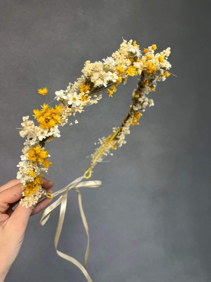 someone is holding flowers in their hand and it looks like they are made out of dried flowers