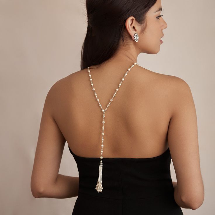 The Carina necklace is the perfect piece for adding glamour to the front and back of your bridal gown. Made to be versatile, this Czech glass pearl necklace can be worn with the crystal-encrusted tassel facing front or at the back, leaving an elegant strand of pearls around the front of the neck and accentuating any open-back gown. All jewelry is made to order in our New York City design studio. Please allow 7-14 business days for production from the order date. Measurements: 30.75" L Long Pearl Pendant Necklace For Parties, Elegant Single Strand Lariat Drop Necklace, Elegant Lariat Drop Necklace With Single Strand, Elegant Beaded Necklace With Pearl Pendant For Party, Elegant Pearl Lariat Necklace For Wedding, Elegant Pearl Beaded Necklace With Pearl Drop, Elegant Pearl Lariat Backdrop Necklace, Elegant Party Beaded Necklace With Pearl Pendant, Long Pearl Necklace For Evening