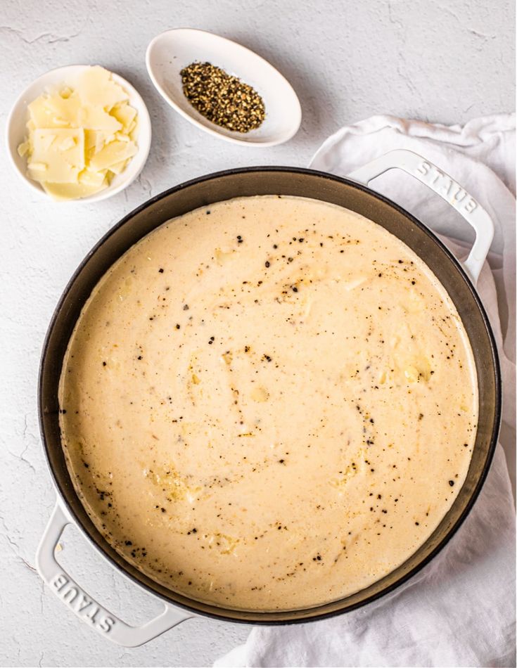 a pan filled with food sitting on top of a white counter next to two spoons