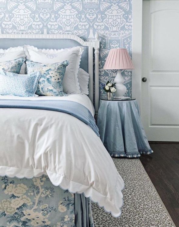 a bedroom with blue and white wallpaper, bedding and pillows on the headboard