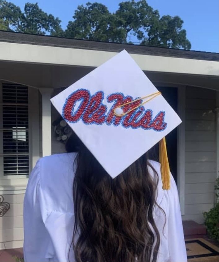 a woman wearing a white graduation cap with the word olem in red and blue letters