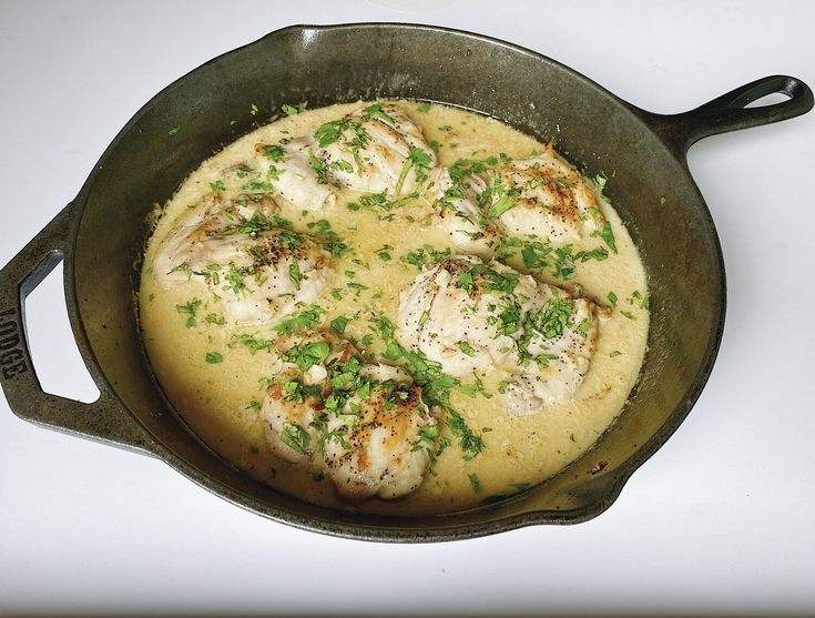 a skillet filled with food on top of a white counter next to a knife