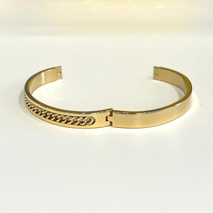 Bring home this magnificent bangle bracelet. Featuring a polished curb chain inlay design this bracelet is made from stainless steel. This is a seriously pretty bangle that is easy way to dress up any outfit, it makes a beautiful gift or a special treat for yourself.- Metal: Stainless Steel.- Plating: 18k Gold plated.- Inner Diameter: 64 mm.- Width: Aprox. 8 mm.- Clasp: Snap Closure.- Circumference Inches: 7.85 Ships in a Balara Gift Pouch.Available in Gold.SKU# B1781 Trendy Stainless Steel Chain Bracelet With Gold Chain, Adjustable Metal Bangle, Tarnish Resistant, Trendy Stainless Steel Gold Chain Bracelet, Modern Stainless Steel Bracelet With Gold Chain, Trendy Tarnish Resistant Stainless Steel Bracelets, Trendy Stainless Steel Gold Bracelet With Adjustable Chain, Gold Stainless Steel Bracelet With Oyster Clasp, Trendy Gold-plated Tarnish-resistant Bangle, Metal Cuban Link Bracelet With Gold Chain