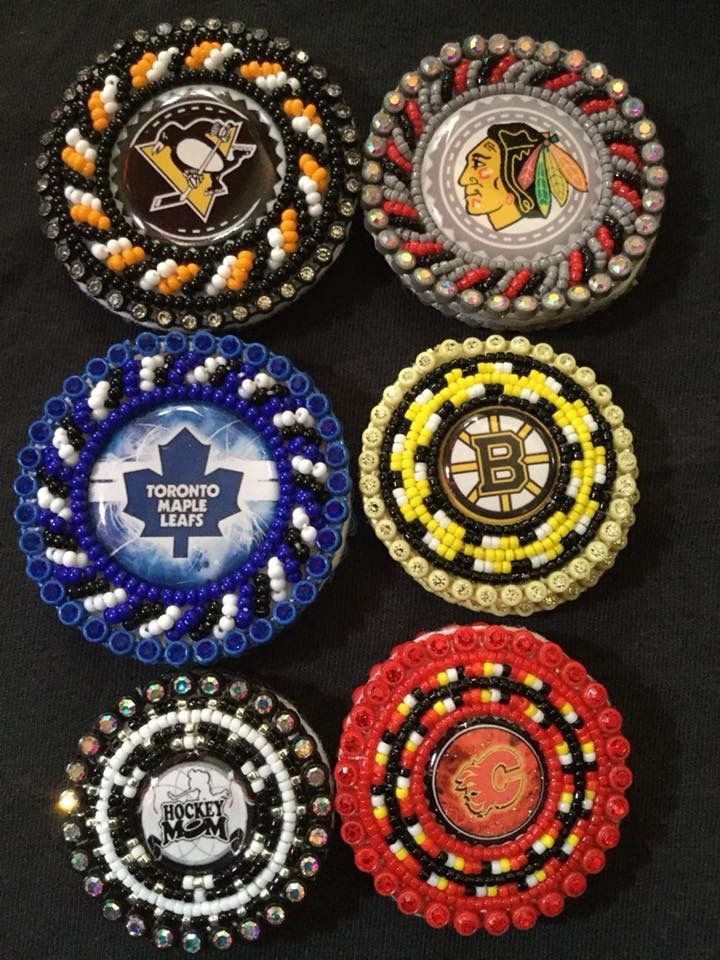 six beaded hockey pucks are arranged on a black tablecloth with the logo of different sports teams