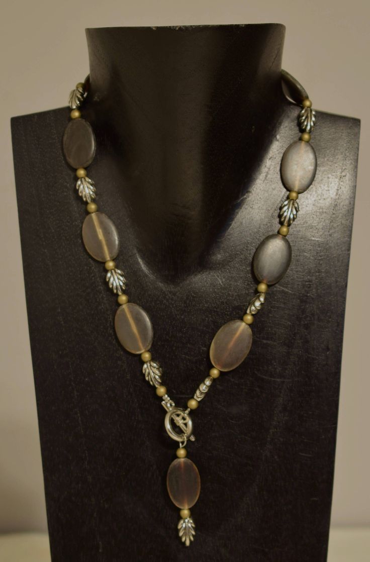 This lovely Handmade Oval Horn Pendant Front Toggle Necklace with Silver Leaf Beads and Bronze Beads all strung on wire with  a with a silver toggle clasp. A truly a wonderful necklace that will compliment any outfit, is lightweight and comfortable  to wear.  A great gift to give that special someone. Necklace with Pendant 22 Inches Long Beads 19.5 Inches Long Brown Horn  25mm Long 18mm Wide Silver Leaves 12mm Long 10mm Wide Bronze Beads 4mm Round AT BACARA WE STAND BEHIND ALL OF OUR MERCHANDISE.  FULL MONEY BACK GUARANTEE WILL BE PROVIDED FOR DISSATISFIED CUSTOMERS. YOUR SATISFACTION IS OUR MAIN GOAL, AND WE THANK YOU FOR SHOPPING AT BACARA. A195 Horn Pendant Necklace, Cowrie Shell Necklace, Leaf Beads, Necklace With Pendant, Silver Leaves, Horn Pendant, Toggle Necklace, Jade Ring, Shell Necklaces