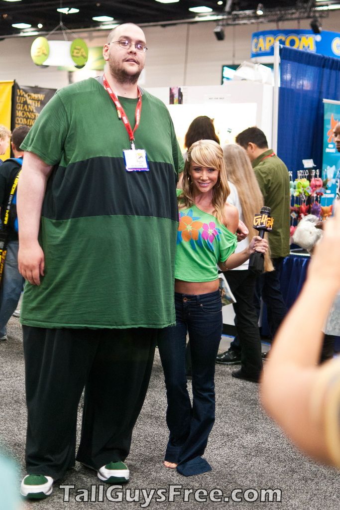 a man and woman standing next to each other in front of a crowd at a convention