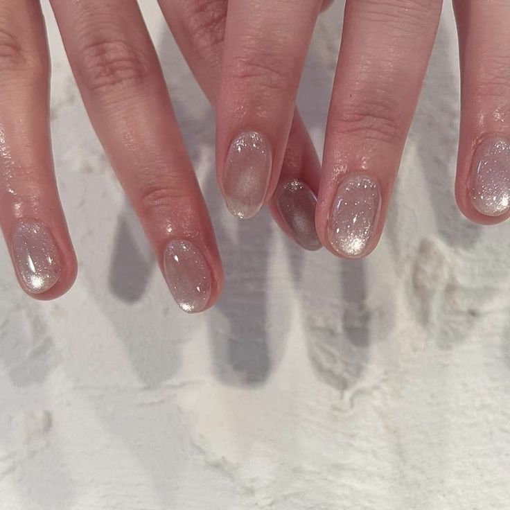 a woman's hand with white and silver nail polish on it, in the snow