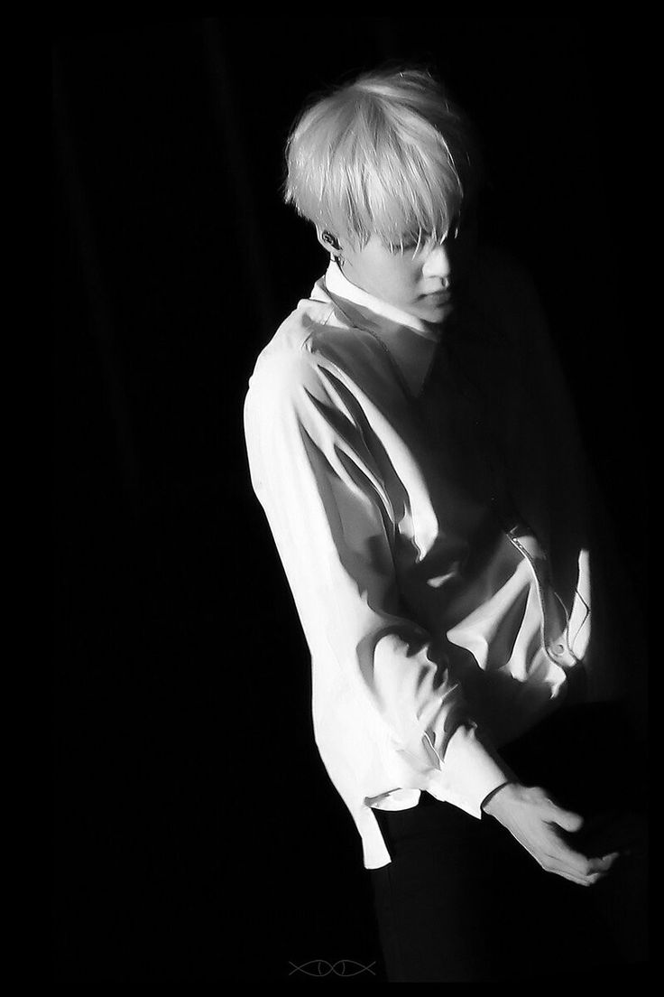 black and white photograph of a person with blonde hair wearing a shirt in the dark