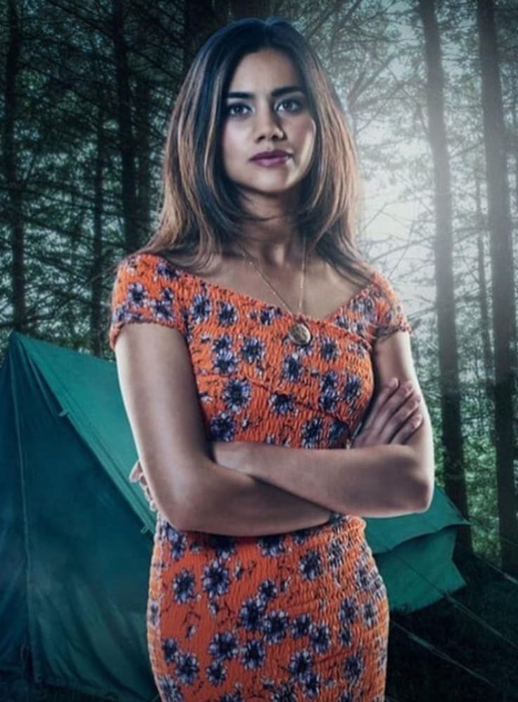 a woman standing in front of a tent with her arms crossed and looking at the camera