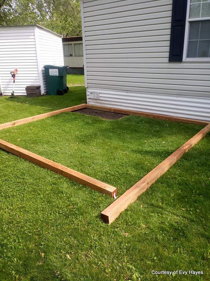 a wooden bed frame sitting in the grass