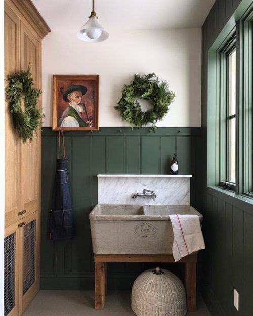 a bathroom with green painted walls and wood paneling, including a white sink in the center