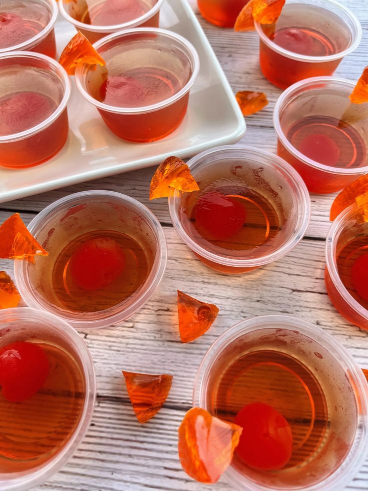 several cups filled with liquid sitting on top of a white tray next to orange peels