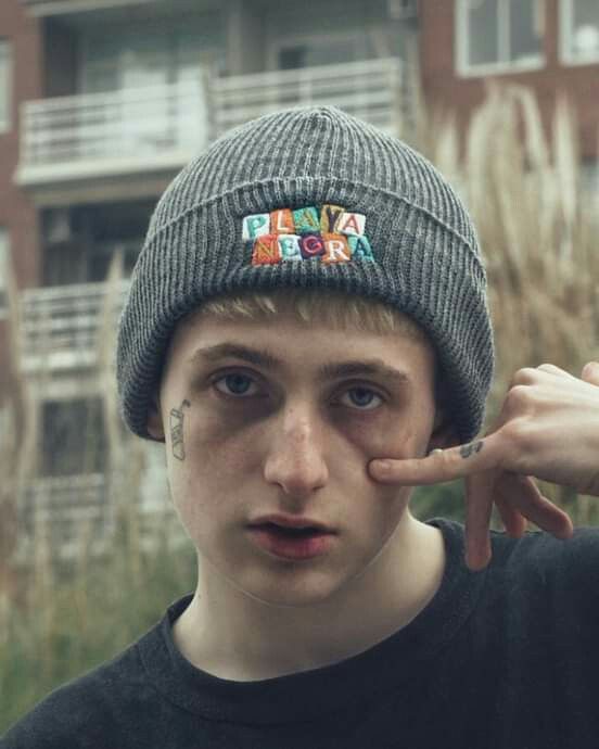 a young man wearing a beanie hat with patches on it