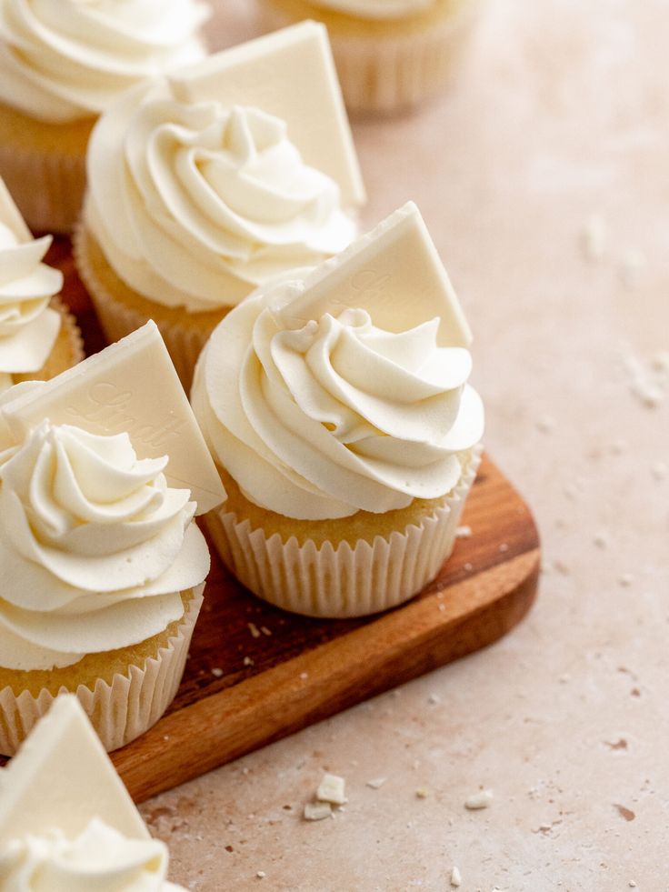 cupcakes with white frosting on a wooden board