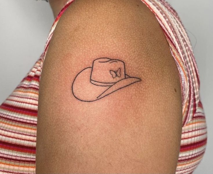 a woman's arm with a hat tattoo on the left side of her shoulder