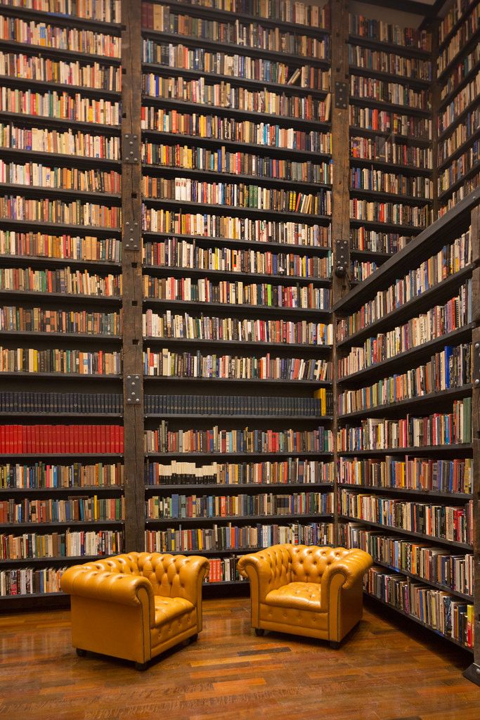 two yellow leather chairs in front of a bookshelf filled with lots of books