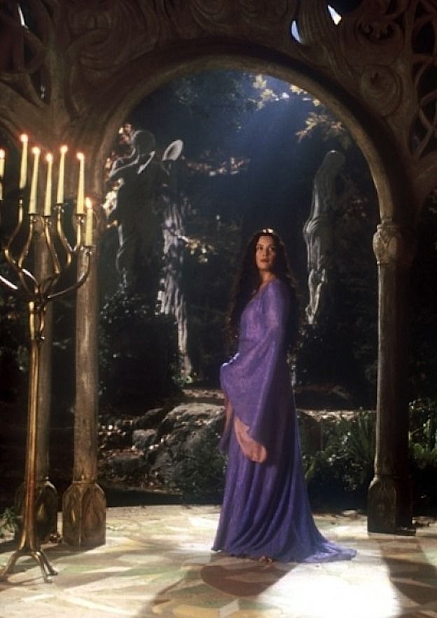 a woman in a purple dress standing under an archway